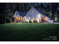 Stunning two-story home featuring a lush green lawn, inviting front porch, and attached garage with a well-lit exterior at 2418 Shuford Rd, Lincolnton, NC 28092