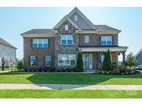 Beautiful two-story brick home with stone accents and a well-manicured front yard at 19012 Beecher Commons Dr, Huntersville, NC 28078