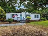 Charming single-story home with a welcoming front porch, beautiful yard, and patriotic American flag at 4833 Verde View Dr, Gastonia, NC 28056