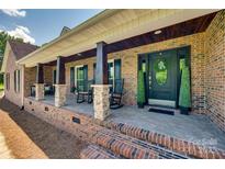 Inviting brick front porch with rocking chairs and decorative columns creates a warm welcome to the home at 1388 Aragon Beach Rd, Rock Hill, SC 29732