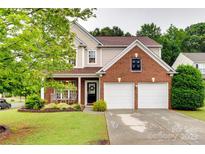 Charming two-story home featuring a brick facade, attached garage, and meticulously landscaped front yard at 2103 Cantata Ct, Matthews, NC 28105