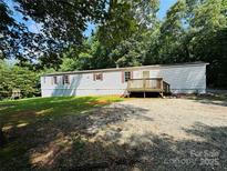Charming single-story home with a gravel yard and wooden deck, nestled amongst lush trees at 4832 Gideon Dr, Lincolnton, NC 28092