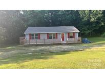 Charming home featuring a spacious wraparound deck, red shutters, and a well-maintained lawn at 2611 Dallas Stanley Hwy, Stanley, NC 28164
