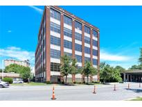 Brick exterior with beautiful, clear blue skies, sidewalks, and traffic cones at The Carter Building at 715 N Graham St # 207, Charlotte, NC 28202