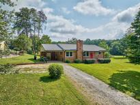Charming brick home with a metal roof, a red door, and a spacious front yard at 7753 Caswell Rd, Stanley, NC 28164