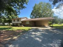 Charming split-level home with a brick facade and covered carport, surrounded by mature trees and a gravel driveway at 12003 Old Beatty Ford Rd, Rockwell, NC 28138