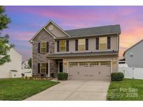 Charming two-story home with a two-car garage, stone accents, and manicured lawn at 12822 Plumleaf Dr, Charlotte, NC 28213