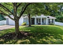 Charming one-story home with a well-manicured lawn and inviting front porch with white columns and mature trees at 13517 Silver King Ct, Huntersville, NC 28078