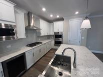 New kitchen features white cabinets, stainless steel appliances and large island with a sink and quartz countertop at 707 Marion Dr, Matthews, NC 28105