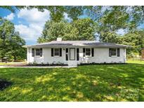 Charming single story home with a well manicured lawn, black shutters, and mature trees overhead at 104 Spargo St, Gastonia, NC 28056