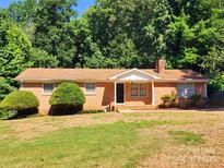 Charming brick ranch home with mature landscaping and inviting front porch on a sunny day at 125 Circle Dr, Mount Holly, NC 28120