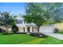 Charming two-story home with black shutters, a well-manicured lawn, and beautiful landscaping around the front at 14739 Cane Field Dr, Charlotte, NC 28273