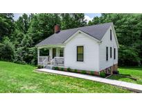Charming white cottage-style home with covered porch and well-maintained front yard surrounded by lush greenery at 2704 Kool Park Ne Rd, Hickory, NC 28601