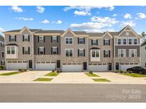 Stylish townhome exteriors showcasing stone accents, complementary siding, and individual garages under a bright sky at 2040 Dornoch Rd, Tega Cay, SC 29708