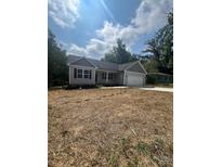 Charming one-story home featuring gray siding, black shutters, and an attached garage, surrounded by a partially unkempt yard at 268 Hatley Ne Cir, Concord, NC 28025