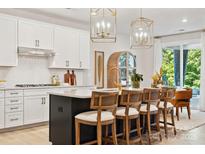 Beautiful kitchen with a black island, white cabinets, light countertops, and stunning gold light fixtures at 4010 Caymen Bay Ct, Tega Cay, SC 29708