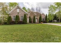 Well-maintained brick home featuring mature landscaping and lush green lawn at 233 Highland Forest Dr, Clover, SC 29710