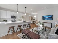 Bright living room with modern white cabinets, island with stools, dining area and a TV at 3316 Cedarhurst Dr, Charlotte, NC 28269