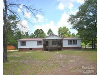 Charming ranch home featuring a welcoming front porch and mature trees at 8221 Feather Run Rd, Kershaw, SC 29067