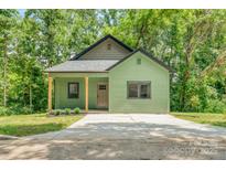 Charming cottage-style home featuring a green exterior, covered porch, and well-manicured lawn at 7 S Coulter Ave, Newton, NC 28658