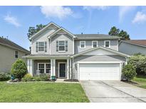 Inviting two-story home with gray siding, a front porch with rocking chairs, and a two-car garage at 409 Bougainvillea Ct, Monroe, NC 28110