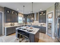 Modern kitchen boasts gray cabinets, an island with seating, stainless steel appliances, and stylish pendant lighting at 18138 Sulton Ter, Huntersville, NC 28078