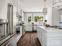 Bright kitchen boasts stainless steel appliances, an island with quartz countertops, and wood flooring at 420 Old Town Village Rd, Waxhaw, NC 28173