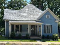 Charming light blue house featuring a inviting front porch with white trim, adding to its curb appeal at 115 E Steele St, Salisbury, NC 28144