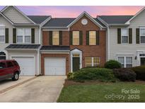 Charming two-story townhouse with red brick, complemented by lush landscaping and a well-maintained lawn at 4208 Carl Parmer Dr, Harrisburg, NC 28075