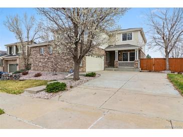 Charming two-story home featuring a brick facade, covered porch, and well-manicured front yard at 20875 E Girard Pl, Aurora, CO 80013