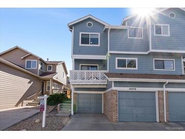 Inviting blue home featuring an attached garage and a charming second-story balcony at 10470 W 83Rd Ave, Arvada, CO 80005