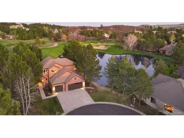 Stunning home with a large driveway, lovely landscaping, and beautiful view of the community golf course and pond at 3216 Country Club Pkwy, Castle Rock, CO 80108