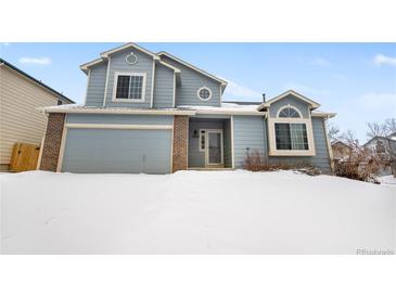 Two-story house with attached garage, snow-covered lawn and brick accents at 4072 S Kirk Way, Aurora, CO 80013