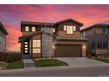 Beautiful two-story home with a two car garage, stone accents, manicured lawn and colorful sunset sky at 14710 Domino Dr, Parker, CO 80134