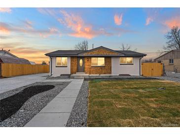 Charming home with updated white brick, wooden features, and a well-maintained front yard, complemented by a colorful sunset sky at 9230 Aspen Dr, Thornton, CO 80229
