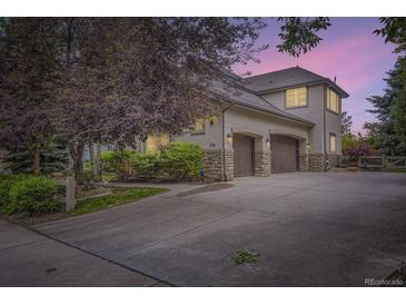 Exterior view of a stucco home featuring a large driveway and a two-car garage with stone accents at 714 Skywalker Pt, Lafayette, CO 80026