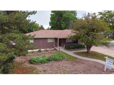 Charming brick home featuring a well-maintained front yard and mature trees at 7140 S Uinta St, Centennial, CO 80112