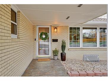 Charming entryway with wreath-adorned door, neat landscaping, and bright windows at 3292 S Wabash Ct, Denver, CO 80231