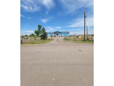 Charming single-story home featuring a covered front porch, attached garage, and spacious front yard at 58117 E 42Nd Dr, Strasburg, CO 80136