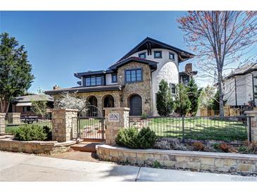 Stunning stone exterior showcasing lush landscaping, gated entry, and unique architectural details on a sunny day at 1030 S Adams St, Denver, CO 80209