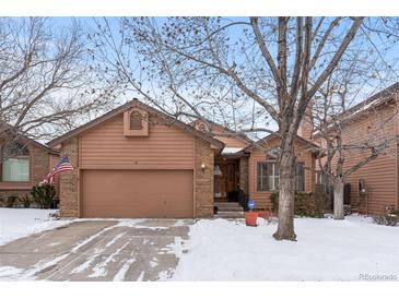 Brick and wood exterior home with a two-car garage and snowy front yard at 7900 E Dartmouth Ave # 76, Denver, CO 80231