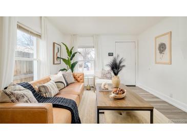 Inviting living room featuring a comfortable leather sofa, stylish decor, and ample natural light at 2774 W Irvington Pl, Denver, CO 80219