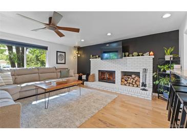 Bright living room features a fireplace, hardwood floors, and large windows at 1746 Shavano St, Longmont, CO 80504