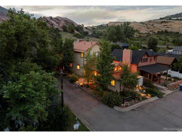 Beautiful home with a stunning rock formation backdrop and colorful lighting on a cloudy day at 109 Bear Creek Ln, Morrison, CO 80465