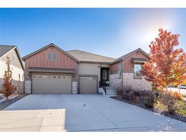 Charming home with a three-car garage, stone accents, and a well-manicured lawn at 7770 Owl Creek Cir, Littleton, CO 80125