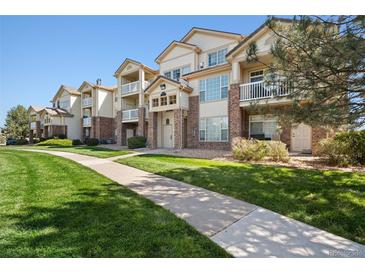 Tan three-story building with multiple balconies and landscaping at 5733 N Gibralter Way # 3-202, Aurora, CO 80019