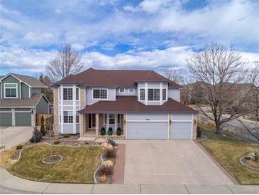 Beautiful two-story home featuring a three-car garage, well-manicured lawn, and classic architectural details at 7084 Moss Ct, Arvada, CO 80007