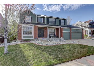 Charming two-story home with brick and green siding, a well-manicured lawn and a two car garage at 1150 W 127Th Ct, Denver, CO 80234