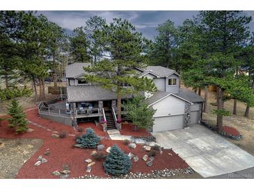 Charming two-story home with a well-manicured yard and inviting deck, nestled among mature trees at 1334 Solitude Ln, Evergreen, CO 80439