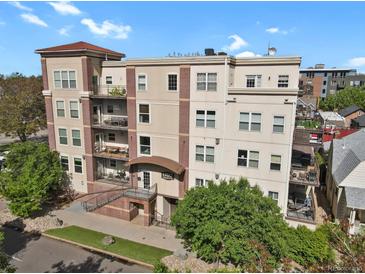 A beautiful multi-story condo building with a brick facade and landscaped grounds under a sunny sky at 1780 N Washington St # 405, Denver, CO 80203
